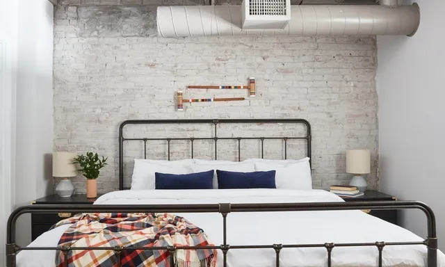 a bedroom with a bed and a potted plant on dresser