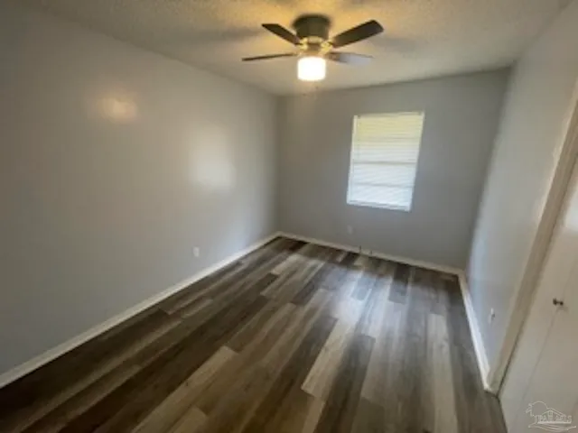 an empty room with wooden floor fan and windows
