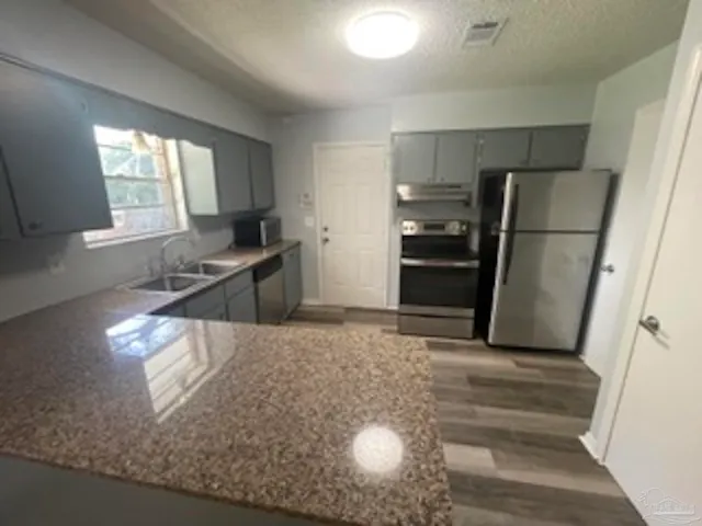 a view of a kitchen with a stove fridge and wooden floor