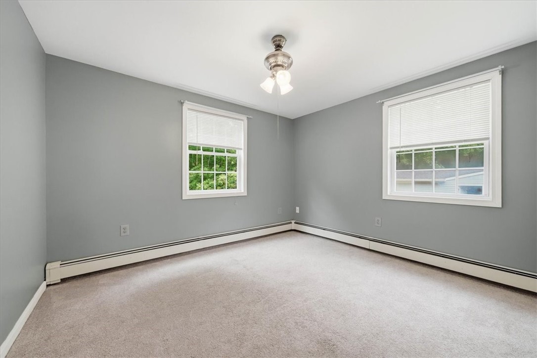 214 Anan Wade Road Glocester, RI 02857 - Photo 22 of 50 Comfortable and versatile, this second bedroom features soft carpeting, a ceiling fan and windows overlooking the backyard retreat.