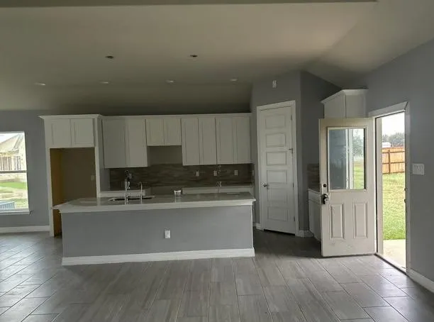 a living room with stainless steel appliances a kitchen island hardwood floor and a sink
