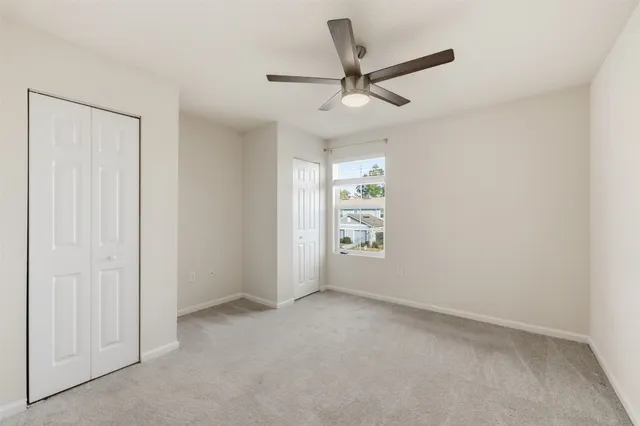 an empty room with windows and fan