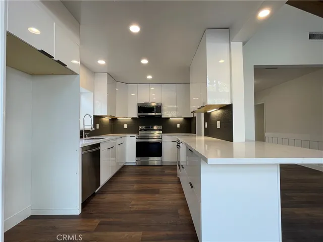 a kitchen with stainless steel appliances kitchen island wooden cabinets and a wooden floor