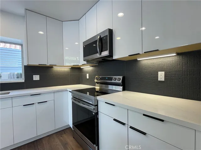 a kitchen with stainless steel appliances granite countertop a sink a stove a refrigerator a microwave oven with wooden floor and cabinets