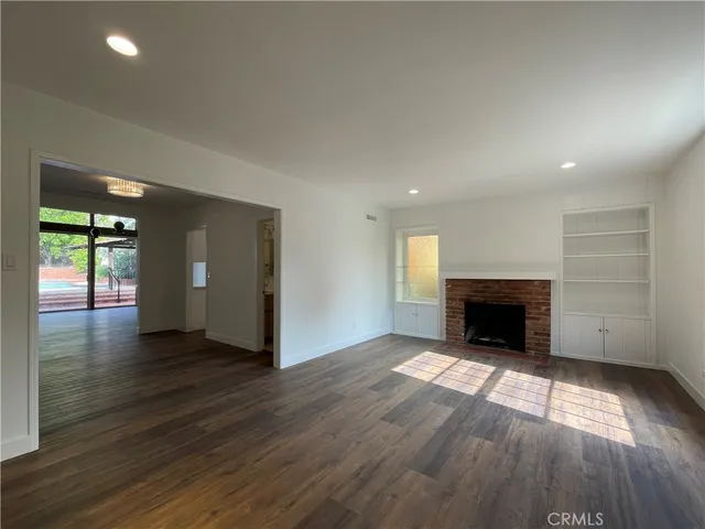 an empty room with wooden floor fireplace and windows