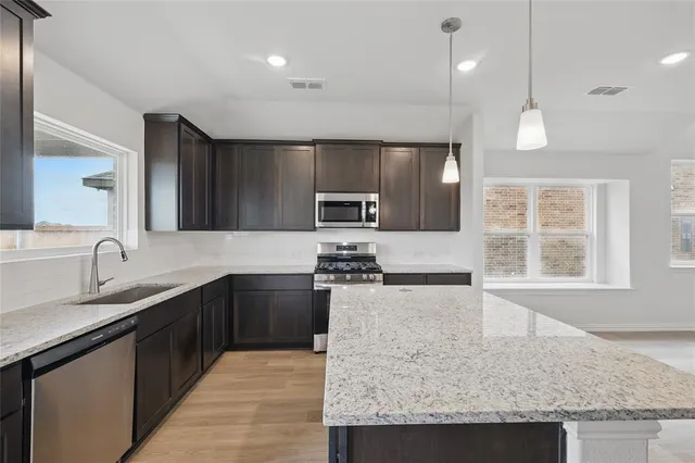 a large kitchen with granite countertop a sink and dishwasher a stove top oven with wooden floor