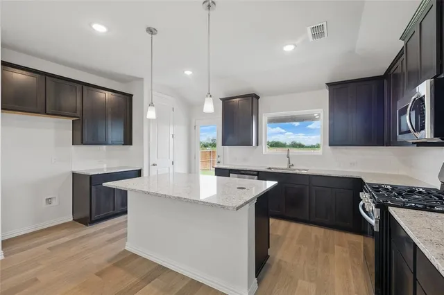 a kitchen with stainless steel appliances granite countertop a sink a stove and kitchen island