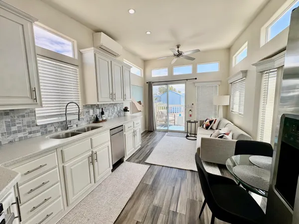 a large white kitchen with cabinets a sink a window and stainless steel appliances