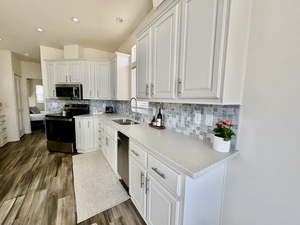a kitchen with kitchen island granite countertop a sink a counter top space appliances and cabinets