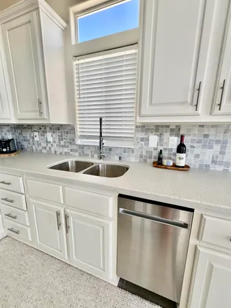a kitchen with white cabinets and sink
