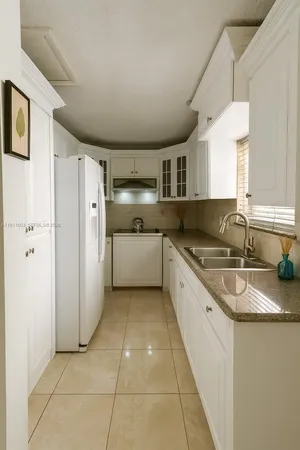 a large kitchen with granite countertop a sink and a refrigerator