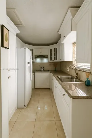 a large kitchen with granite countertop a sink and a refrigerator