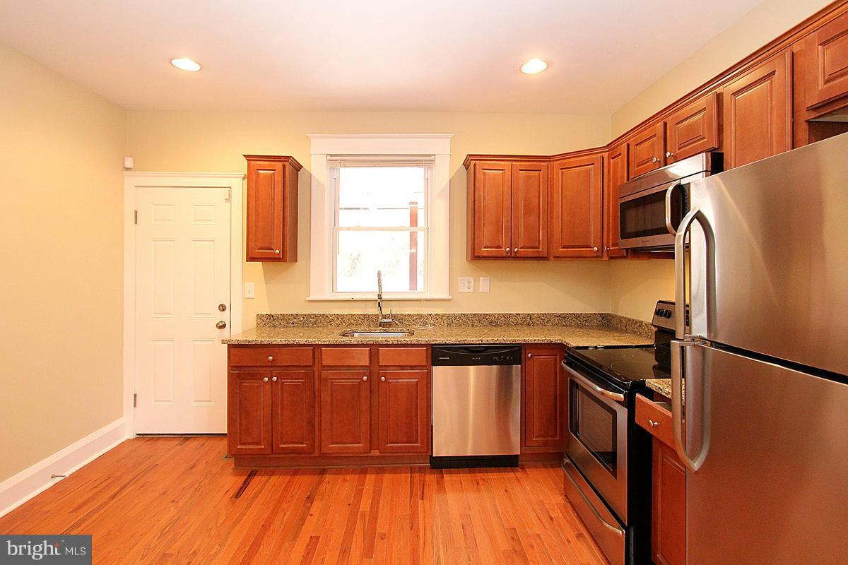 3106 Rueckert Avenue Baltimore, MD 21214 - Photo 10 of 29 a kitchen with stainless steel appliances granite countertop a refrigerator a sink dishwasher and wooden cabinets with wooden floor