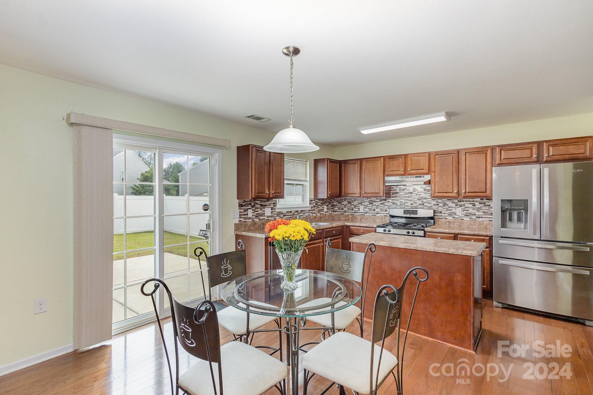 714 Waterlemon Way Monroe, NC 28110 - Photo 14 of 38 a kitchen with stainless steel appliances granite countertop a stove a refrigerator a dining table and chairs with wooden floor