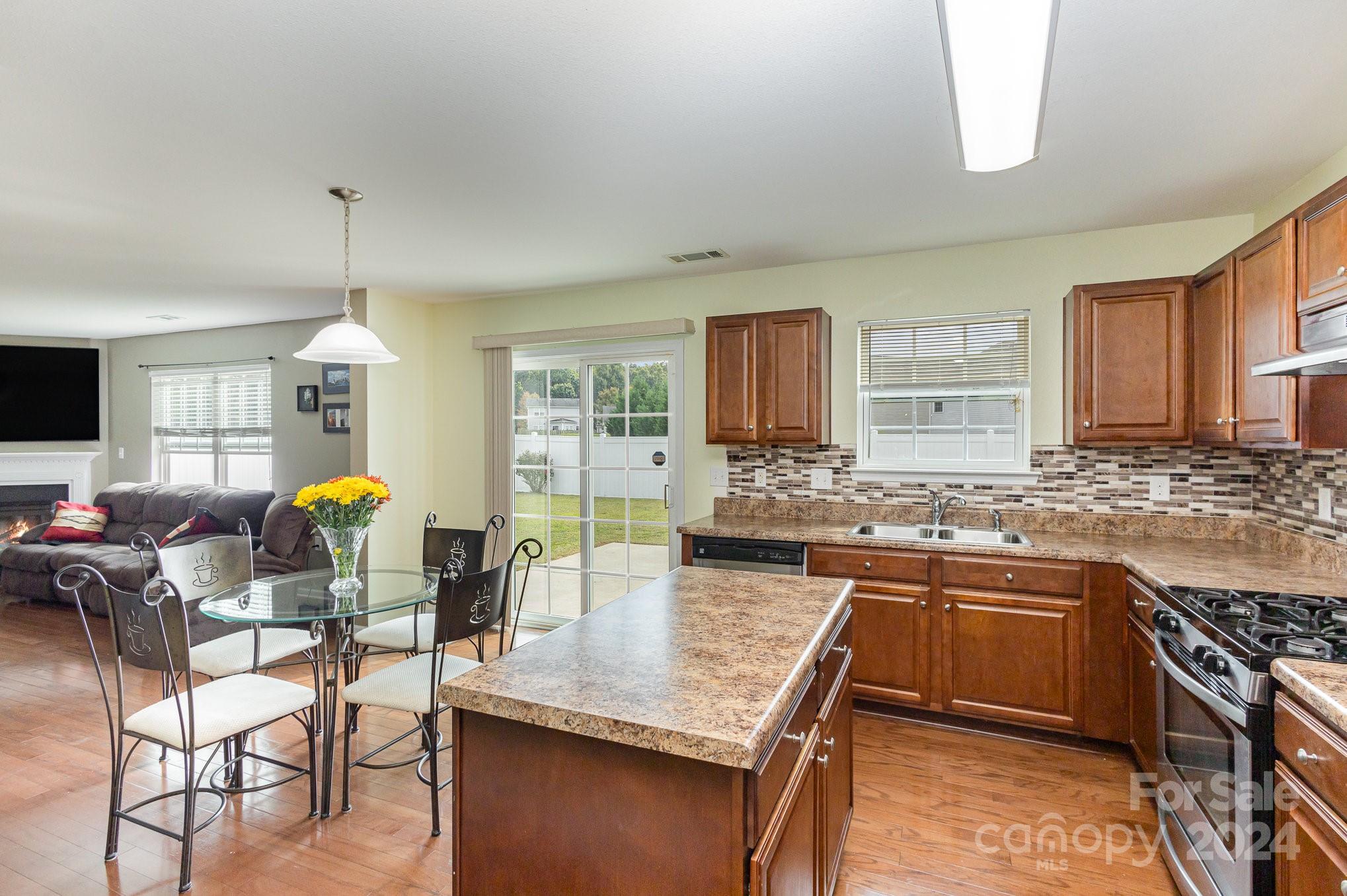 714 Waterlemon Way Monroe, NC 28110 - Photo 15 of 38 a kitchen with stainless steel appliances granite countertop a stove top oven a sink dishwasher a dining table and chairs with wooden floor