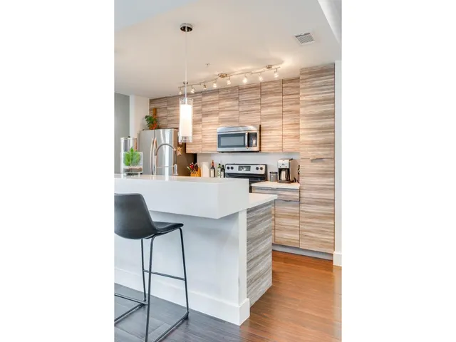 a kitchen with kitchen island a stove a refrigerator a dining table and chairs with wooden floor