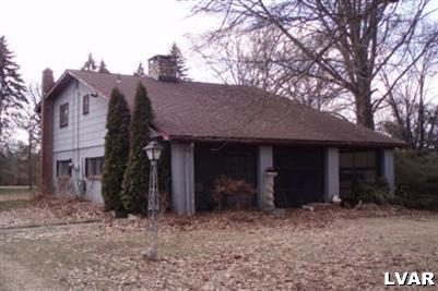a view of a house with a yard and large tree