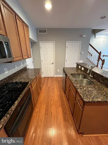a kitchen with sink a stove and wooden floor