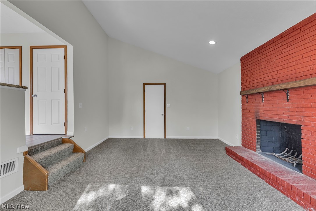 2540 Charney Road University Heights, OH 44118 - Photo 10 of 44 Spacious living area featuring a prominent red brick fireplace with a wood mantle, vaulted ceilings, and gray carpeting