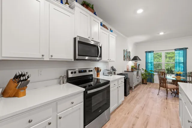 a kitchen with a sink a stove cabinets and wooden floor