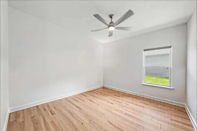 an empty room with a window and ceiling fan
