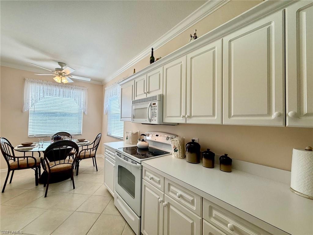 8450 Kingbird Loop, Unit 431 Estero, FL 33967 - Photo 11 of 47 Kitchen with white appliances, crown molding, light countertops, white cabinets, and a ceiling fan