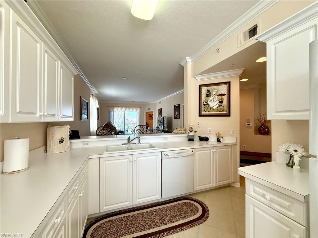 8450 Kingbird Loop, Unit 431 Estero, FL 33967 - Photo 14 of 47 Kitchen featuring crown molding, white cabinets, light countertops, dishwasher, and light tile patterned flooring