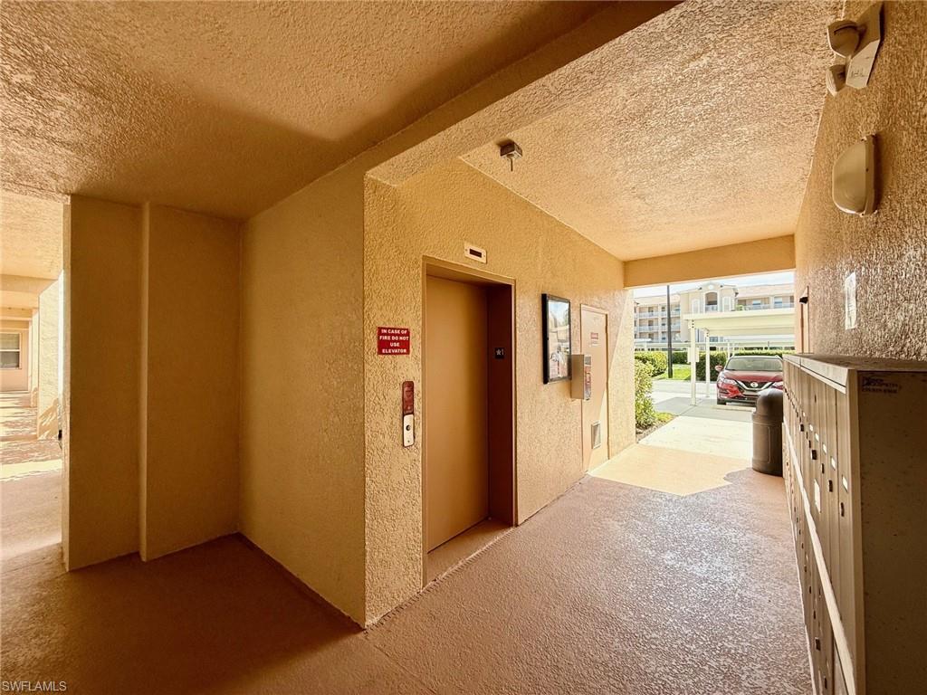 8450 Kingbird Loop, Unit 431 Estero, FL 33967 - Photo 4 of 47 Corridor featuring a textured wall, a textured ceiling, elevator, and carpet
