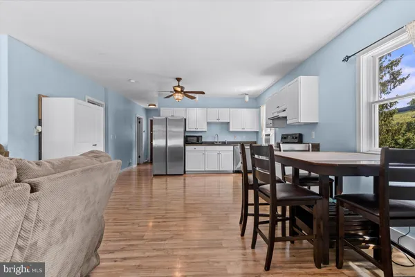 a living room with stainless steel appliances furniture a dining table and kitchen view