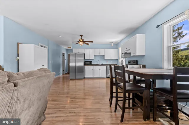 a living room with stainless steel appliances furniture a dining table and kitchen view