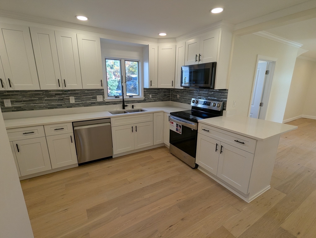 296 Fulton Street, Unit 1 Medford, MA 02155 - Photo 2 of 19 a kitchen with white cabinets sink and stainless steel appliances