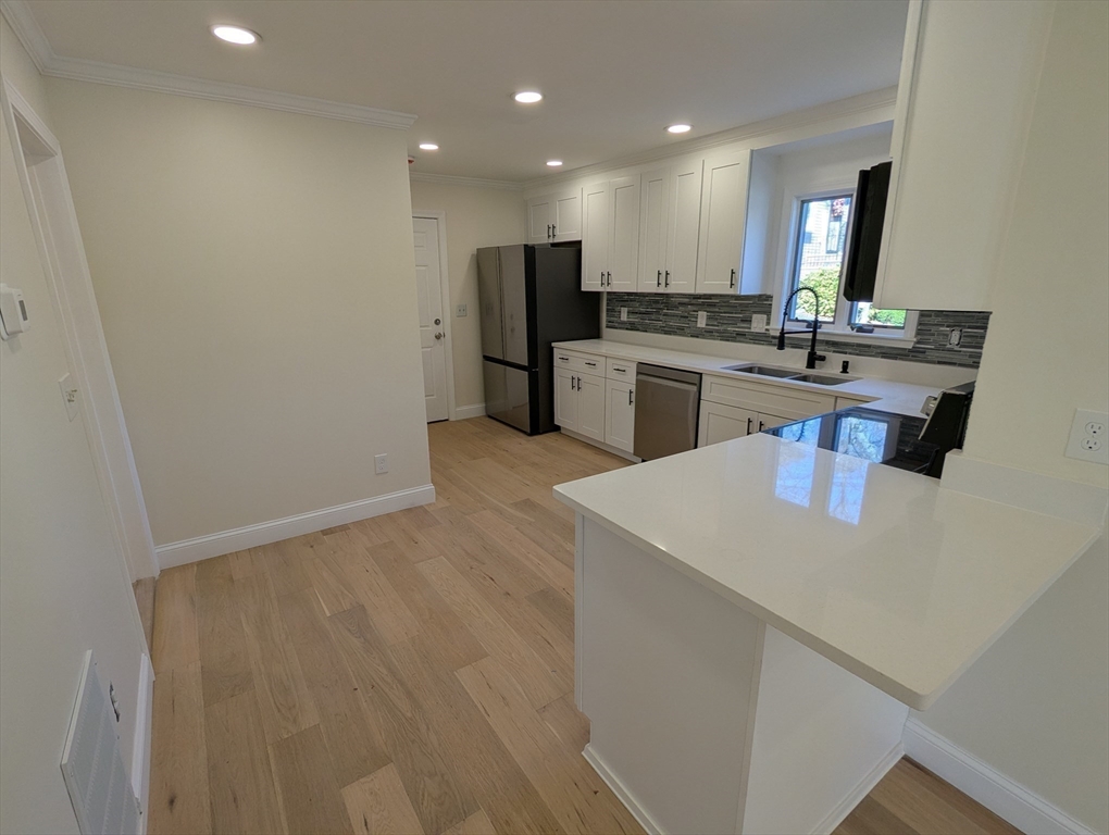 296 Fulton Street, Unit 1 Medford, MA 02155 - Photo 6 of 19 a kitchen with kitchen island a sink stainless steel appliances and cabinets