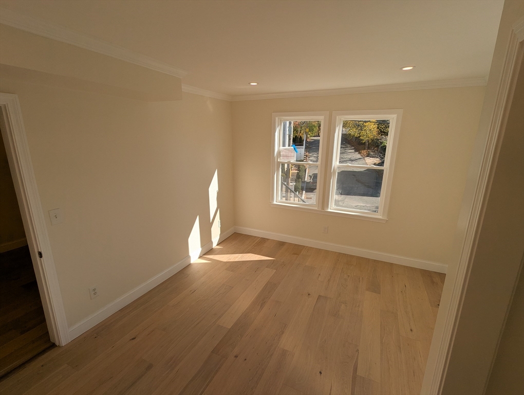296 Fulton Street, Unit 1 Medford, MA 02155 - Photo 10 of 19 an empty room with wooden floor and windows