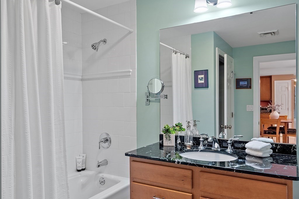95 Conant Street, Unit 304 Concord, MA 01742 - Photo 16 of 23 a bathroom with a granite countertop sink and a mirror a bathtub