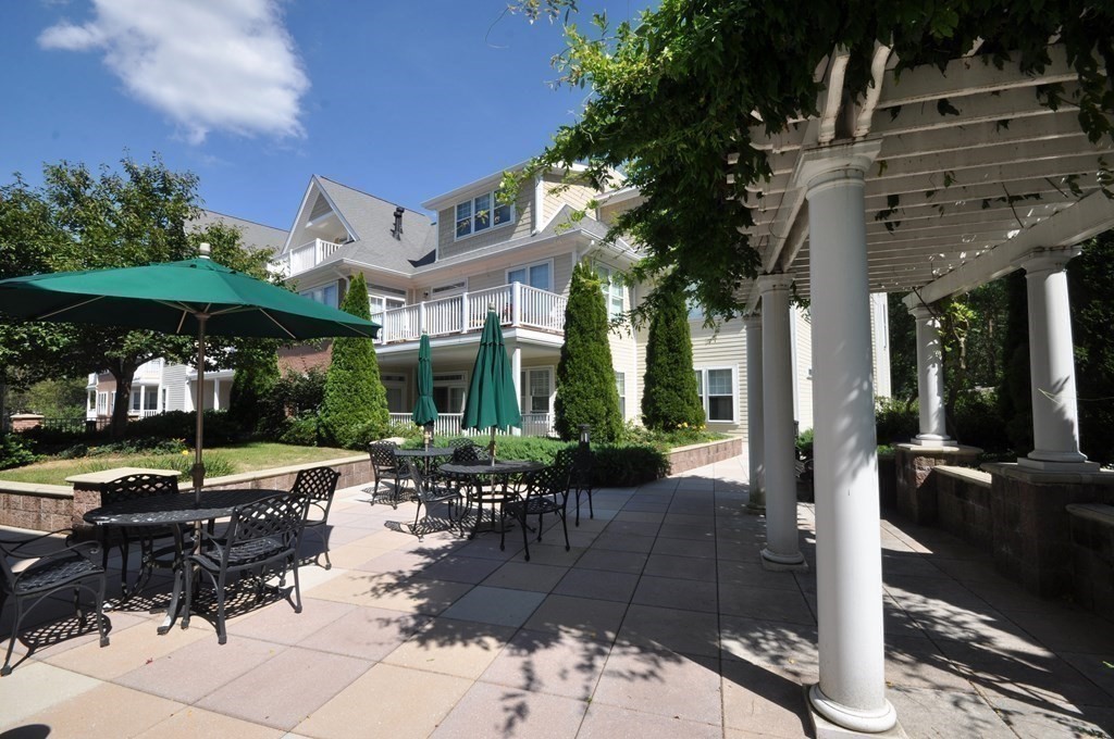 95 Conant Street, Unit 304 Concord, MA 01742 - Photo 23 of 23 a view of a patio with table and chairs potted plants and large tree