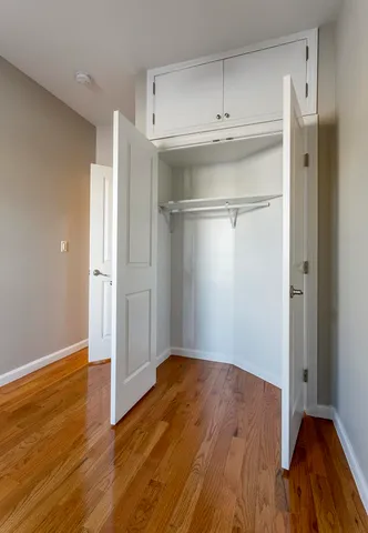 an empty room with wooden floor cabinet and windows
