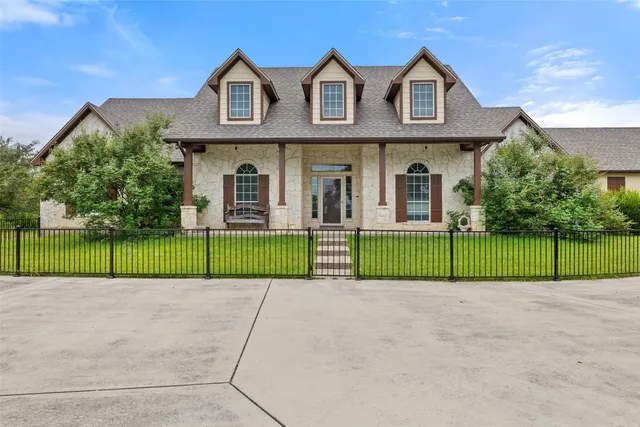 a view of a brick house with a big yard and large trees