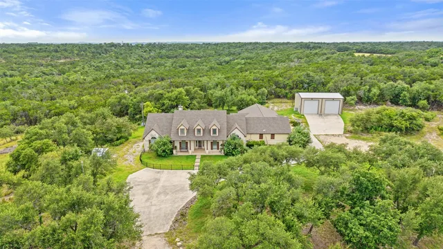 an aerial view of residential houses with outdoor space and trees