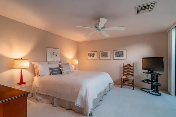 a bedroom with a bed and a flat tv screen on dresser