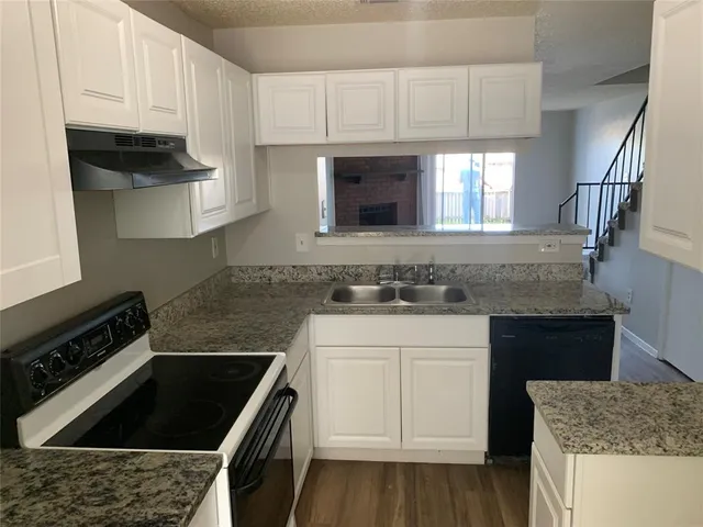 a kitchen with granite countertop a sink stove and cabinets