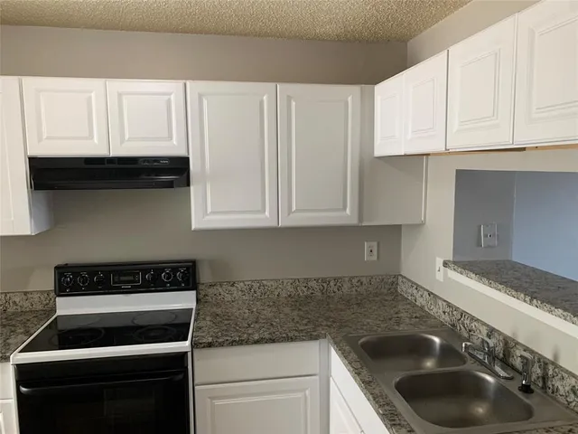 a kitchen with granite countertop white cabinets and a stove top oven