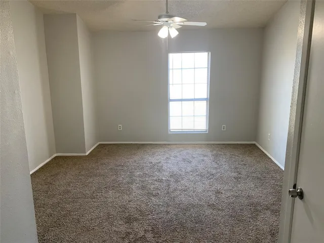 an empty room with windows and chandelier fan