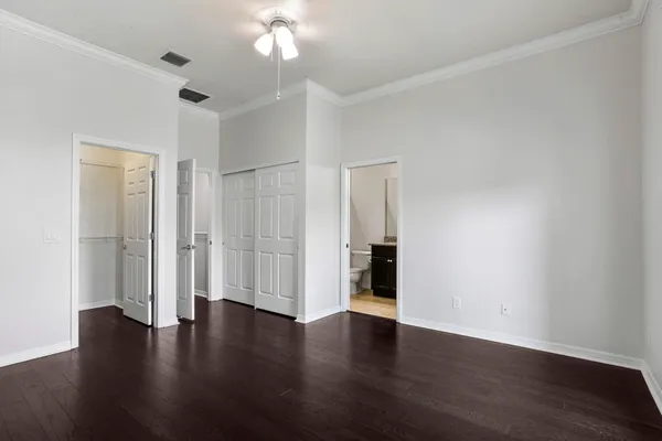 an empty room with wooden floor and a chandelier fan