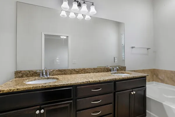 a bathroom with a granite countertop sink a mirror and shower