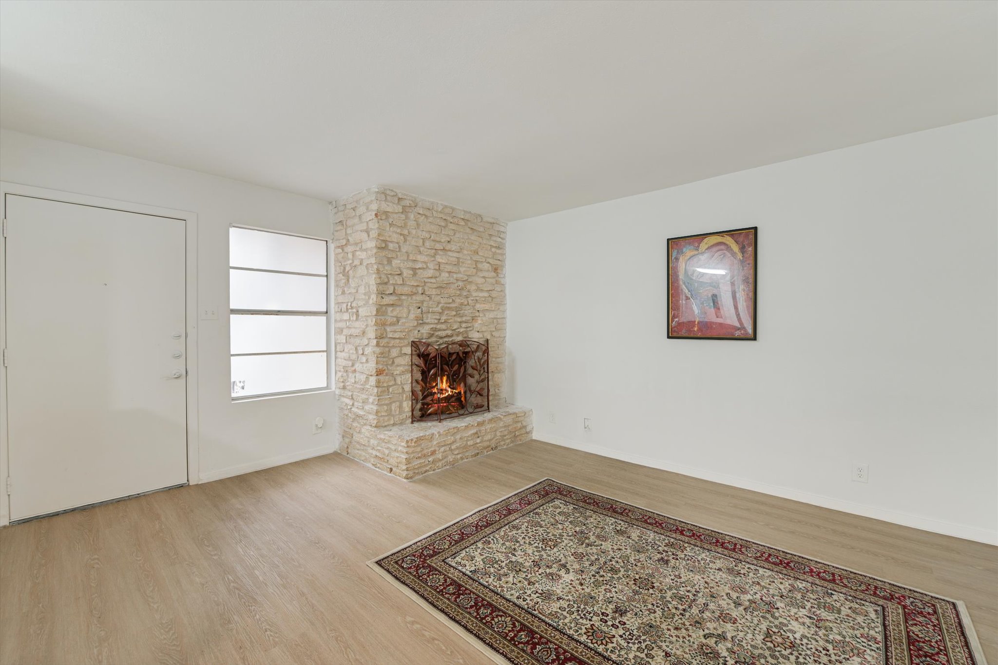 4301 Acropolis Court, Unit B Austin, TX 78759 - Photo 2 of 10 Living area with light wood-style floors and a large fireplace