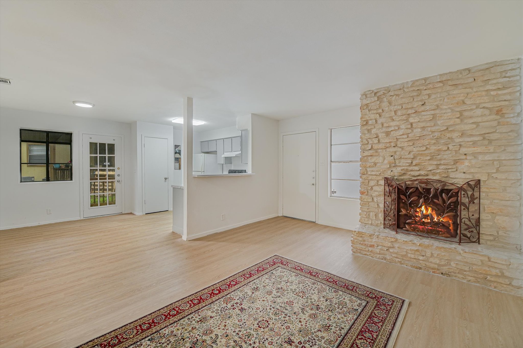 4301 Acropolis Court, Unit B Austin, TX 78759 - Photo 3 of 10 Unfurnished living room featuring light wood-style flooring, a stone fireplace, and plenty of natural light