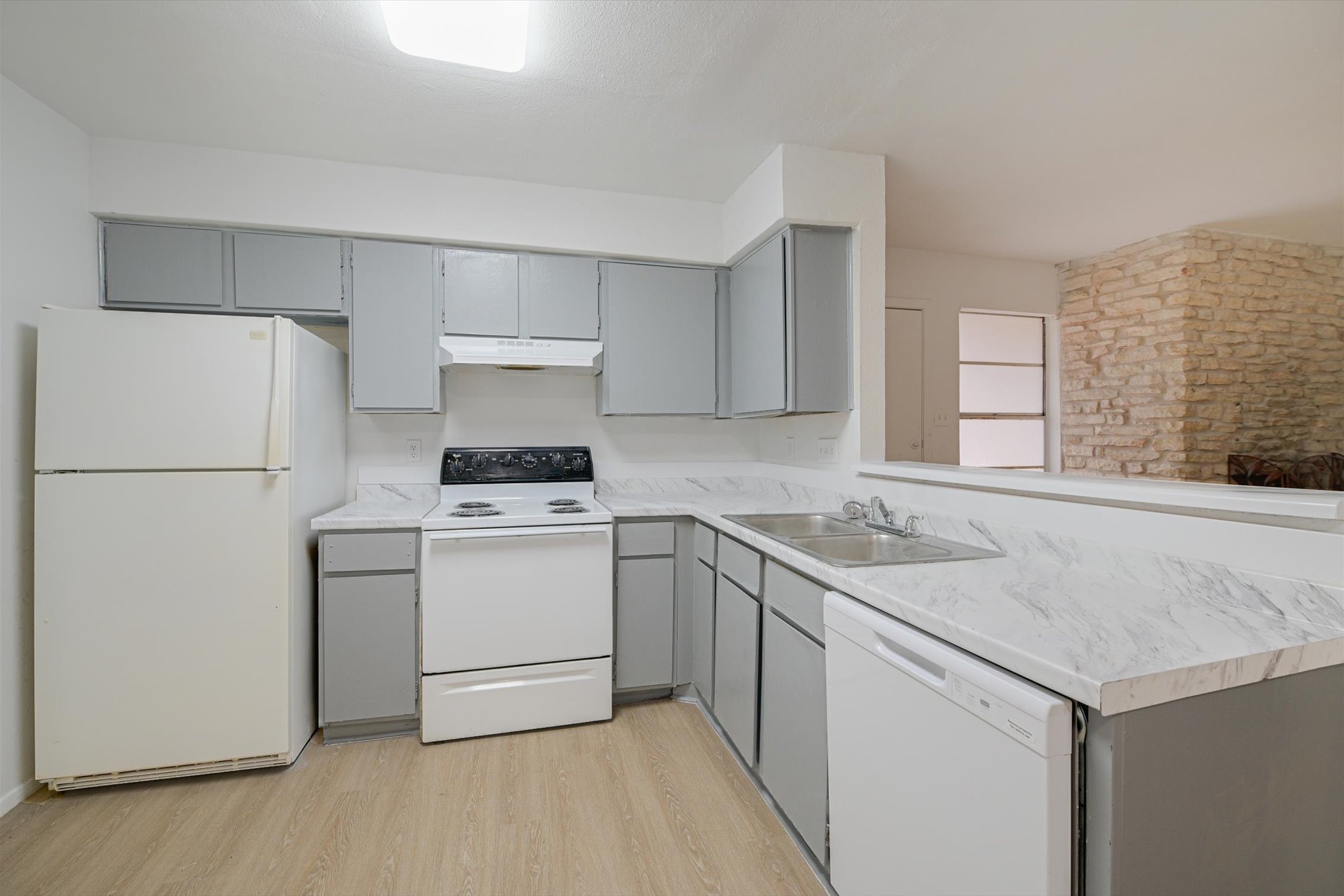 4301 Acropolis Court, Unit B Austin, TX 78759 - Photo 5 of 10 Kitchen with gray cabinetry, white appliances, light countertops, light wood-style flooring, and a peninsula