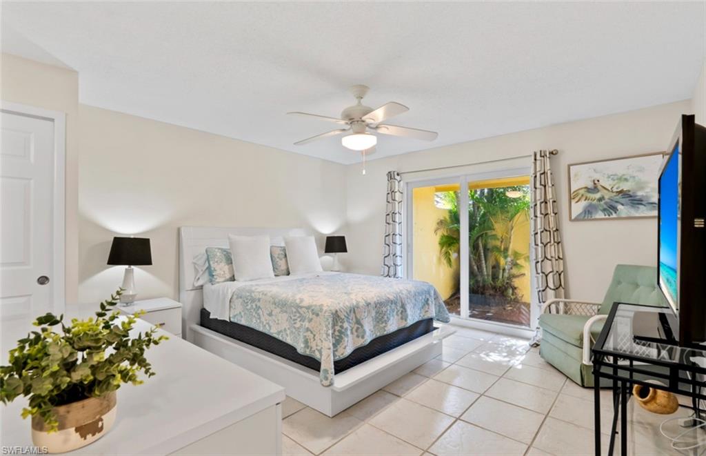 136 Harrison Road, Unit 1 Naples, FL 34112 - Photo 10 of 29 Bedroom featuring sliding glass doors opening to a private outdoor space with lush foliage