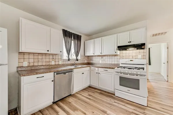 a kitchen with granite countertop white cabinets and white appliances