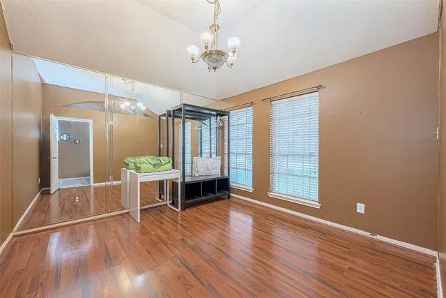 a bedroom with a bed dresser and wooden floor